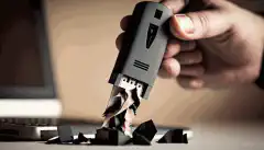 Un'immagine di una persona che tiene in mano una chiavetta USB con un distruggidocumenti sullo sfondo